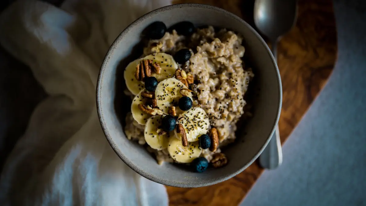 Skål med havregrød toppet med banan, blåbær, pekannødder og chiafrø