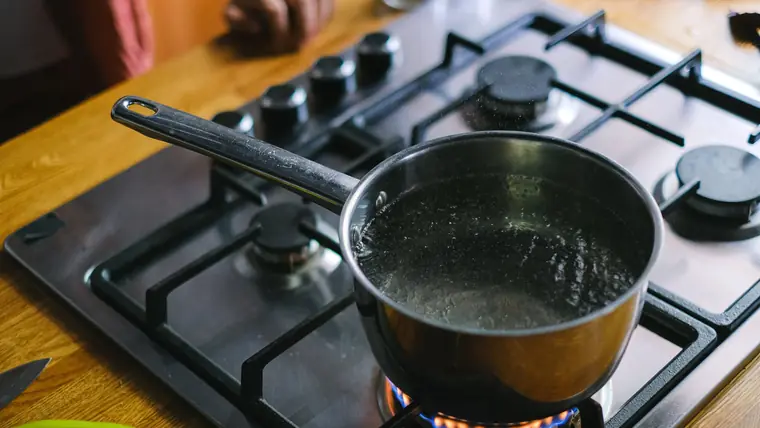 Kogende vand i en gryde af rustfrit stål på et komfur