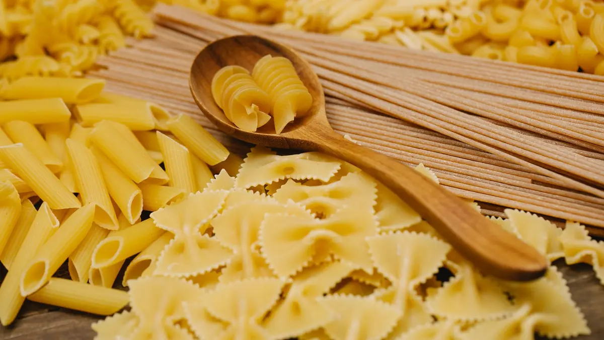 Forskellige slags rå pasta i skåle med en træske ved siden af