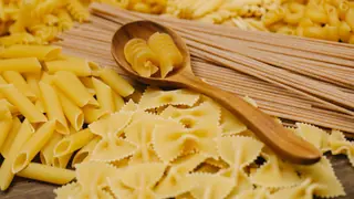 Forskellige slags rå pasta i skåle med en træske ved siden af