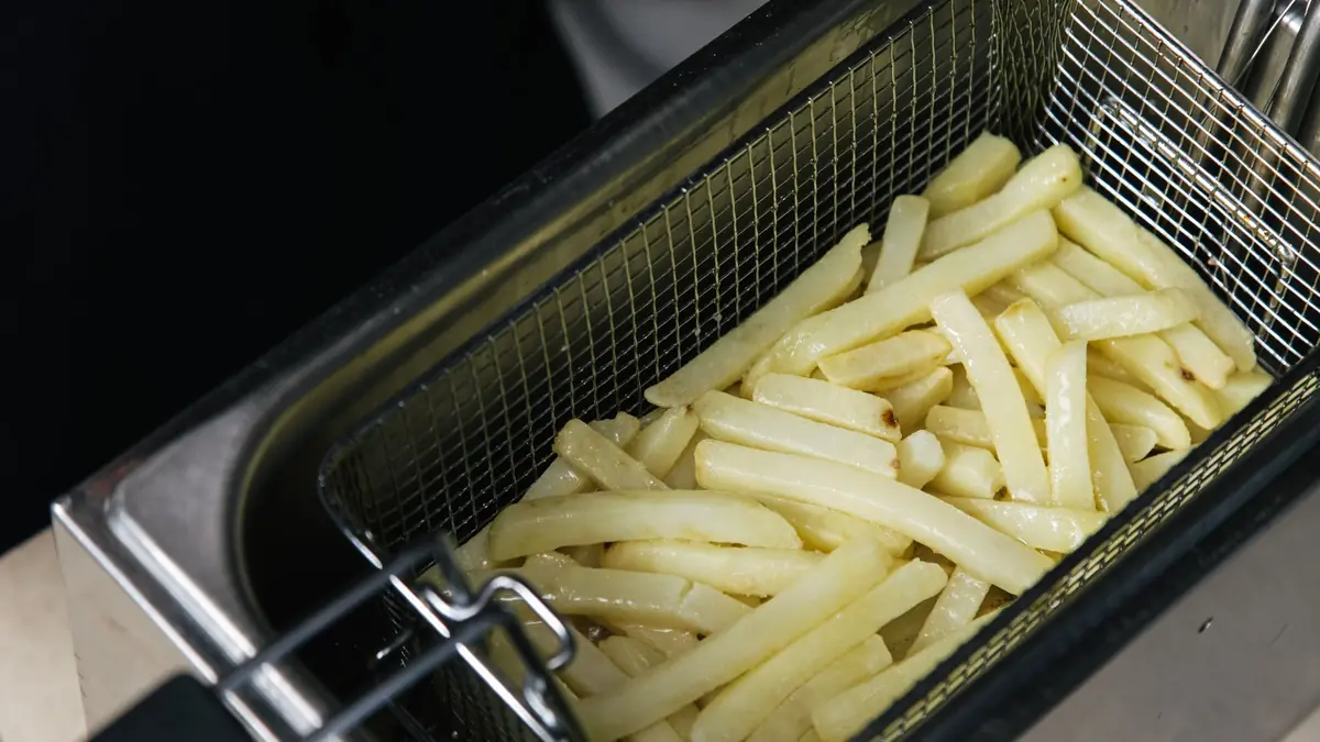 Rå pommes frites i en kurv af metal, klar til tilberedning