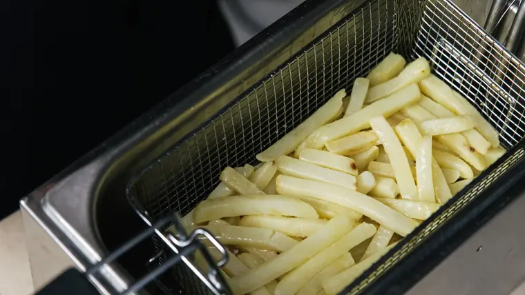 Rå pommes frites i en kurv af metal, klar til tilberedning