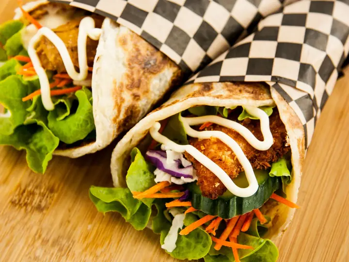 Wraps med kylling, salat, agurk og gulerod skåret over på et bræt
