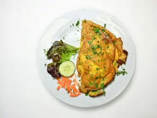 Æggekage på en hvid tallerken med frisk salat, agurk og gulerod, set oppefra