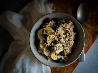 Skål med havregrød toppet med banan, blåbær, pekannødder og chiafrø
