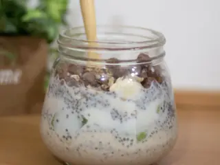 Overnight oats med chiafrø og mælk i et glas på et træbord