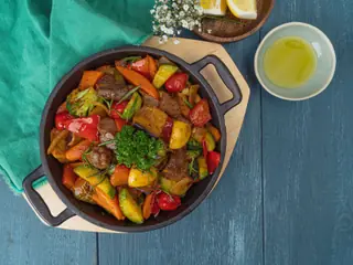 Oksekød stegt med rød og gul peberfrugt, gulerod, squash og broccoli i en sort støbejernspande, set ovenfra